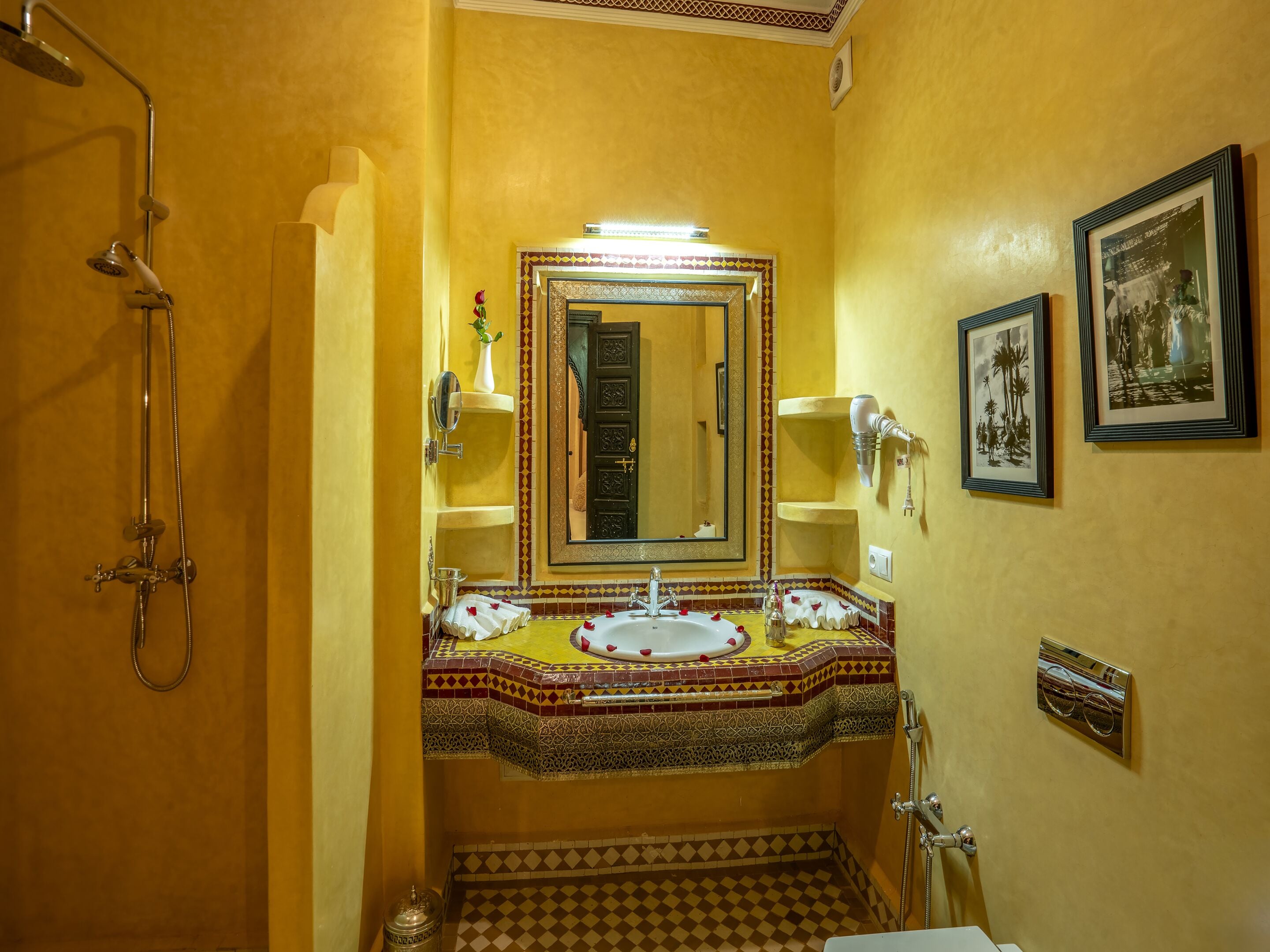 A bathroom with a shower, two sinks, a mirror, and decorative tiles.
