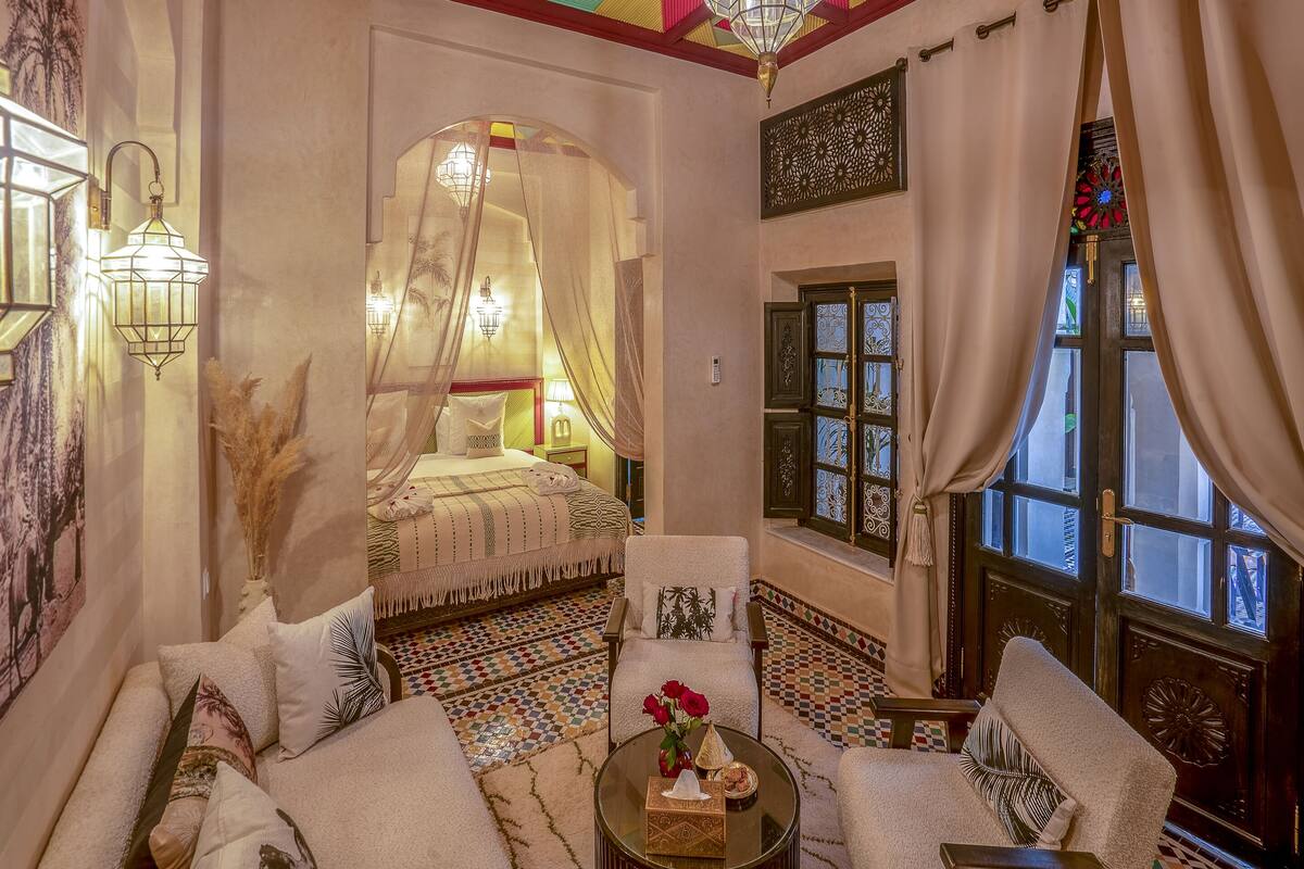 A traditional Moroccan room with a bed, sofa, and a coffee table.