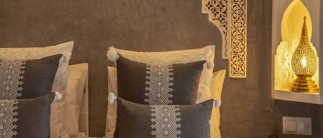 A bed with two pillows, a wall-mounted phone, and a decorative wall light.