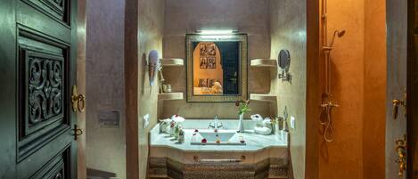 A bathroom with a sink, mirror, and shower.
