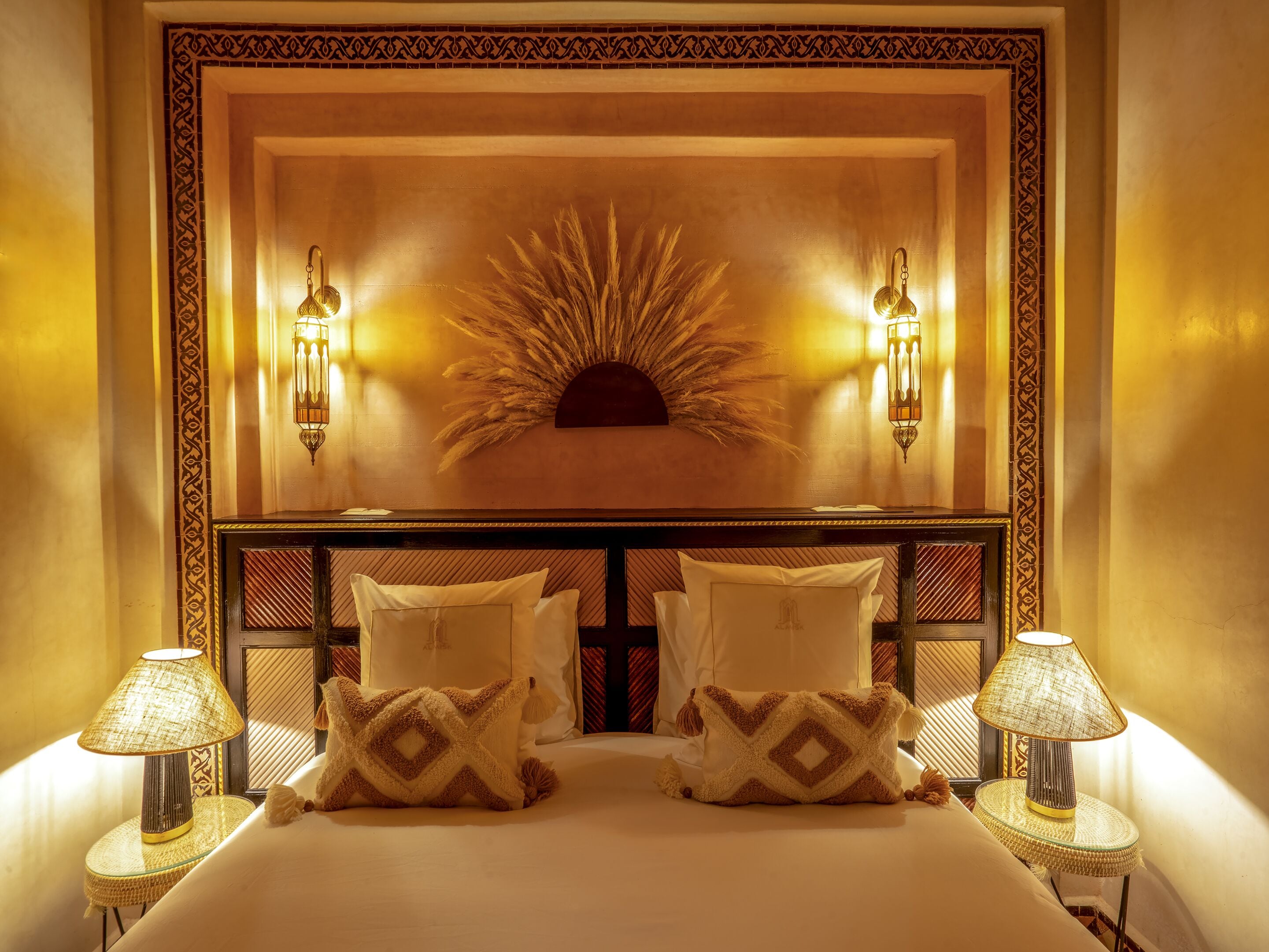 Une chambre d’hôtel avec un grand lit, deux lampes de chevet et un panneau décoratif mural.