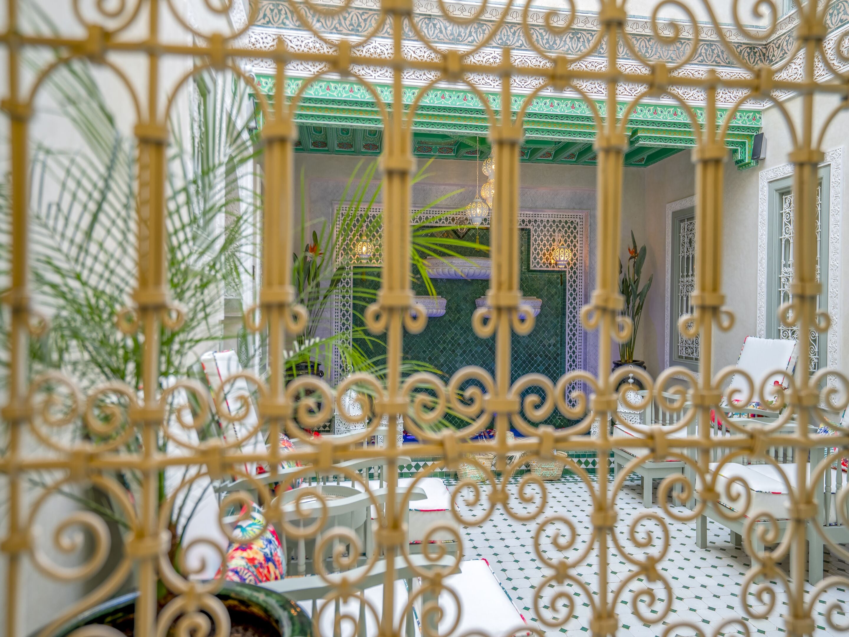 An indoor courtyard with a decorative metal fence, potted plants, and a tiled floor.