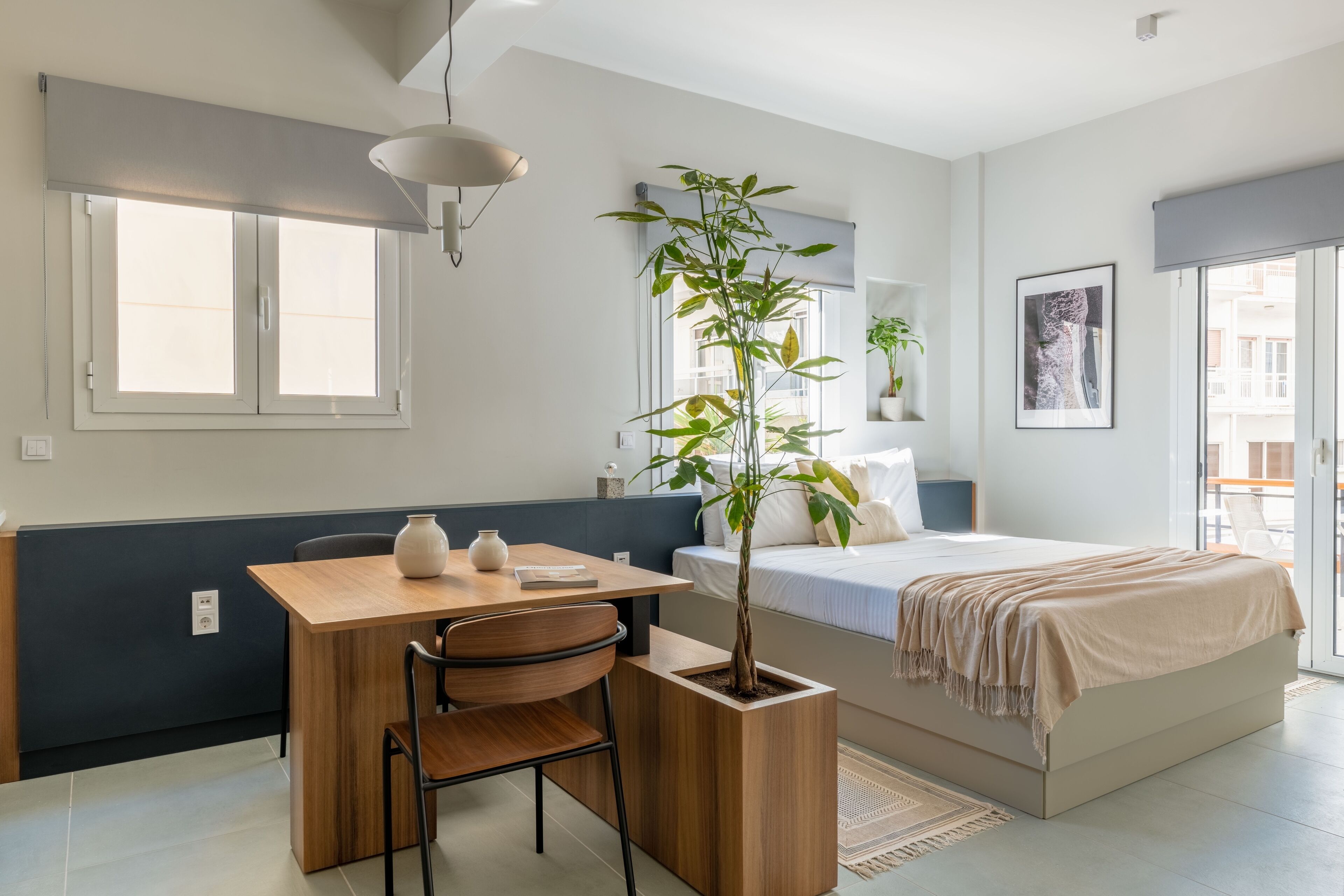 A modern bedroom with a bed, bedside table, chair, and a potted plant.