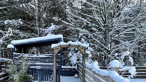 A snow-covered wooden bridge leading to a cabin with a 'PARKING' sign.