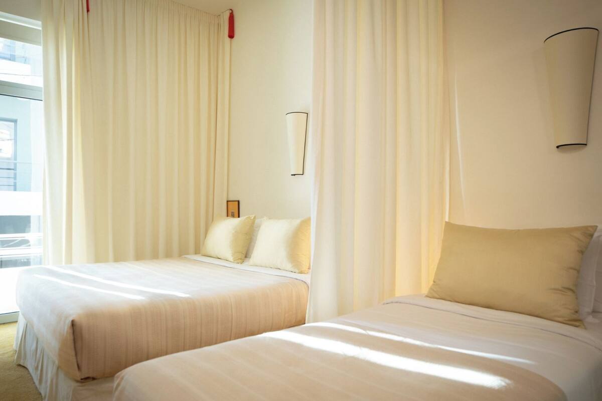 A hotel room with two beds, each with a pillow and a headboard.