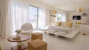 Een moderne hotelkamer met een groot bed, een zithoek met een ronde tafel, en een groot raam met gordijnen.