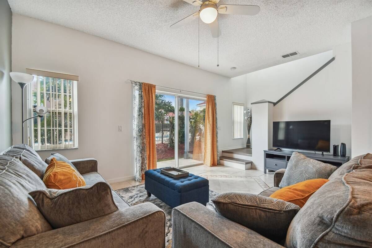 A living room with a sofa set, a television, and a ceiling fan.