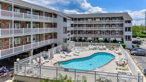Een meerhoog hotel met een zwembad, terras en een omheind dek.