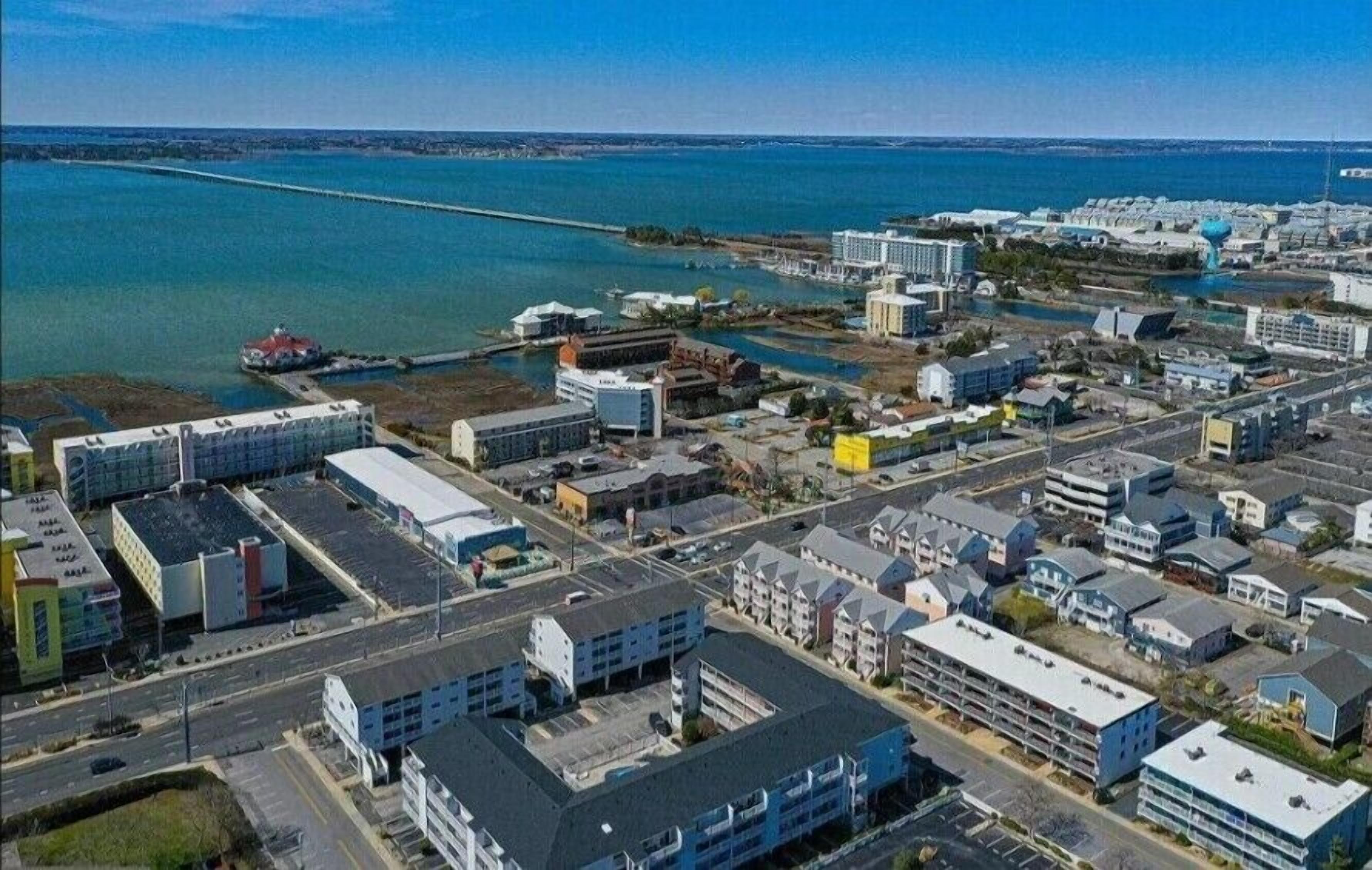 Luchtbeeld van een kustplaatsje met een jachthaven, diverse gebouwen en een brug naar het vasteland.