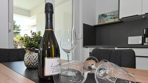 Una botella de vino, dos copas de vino vacías y un recipiente decorativo con forma de piña sobre una mesa de madera.