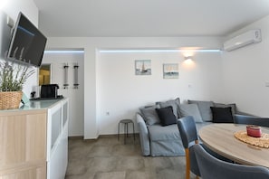 En moderne stue med sofa, sofabord og et fjernsyn ophængt på væggen.