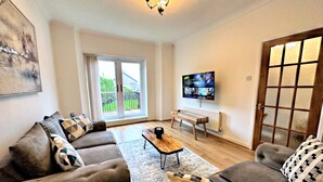 Una sala de estar moderna con un conjunto de sofá, una mesa de centro y un televisor montado en la pared.