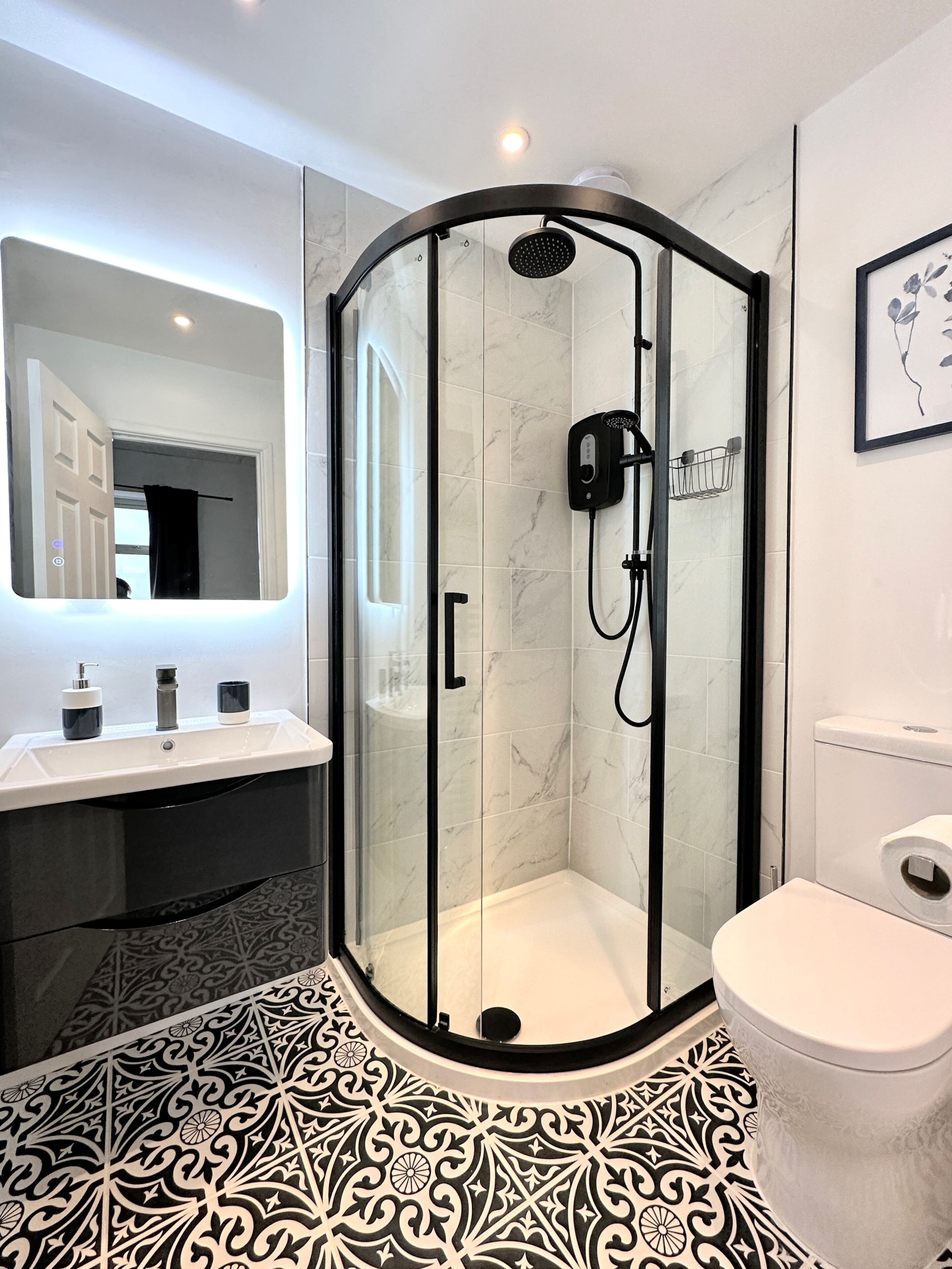 Un baño moderno con ducha de vidrio, lavamanos blanco y retrete.