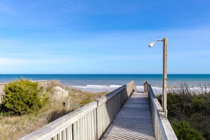 A wooden boardwalk leading to a beach with a clear sky.