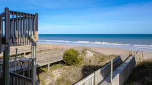 Une promenade en bois qui mène à une plage offrant une vue dégagée sur l’océan.