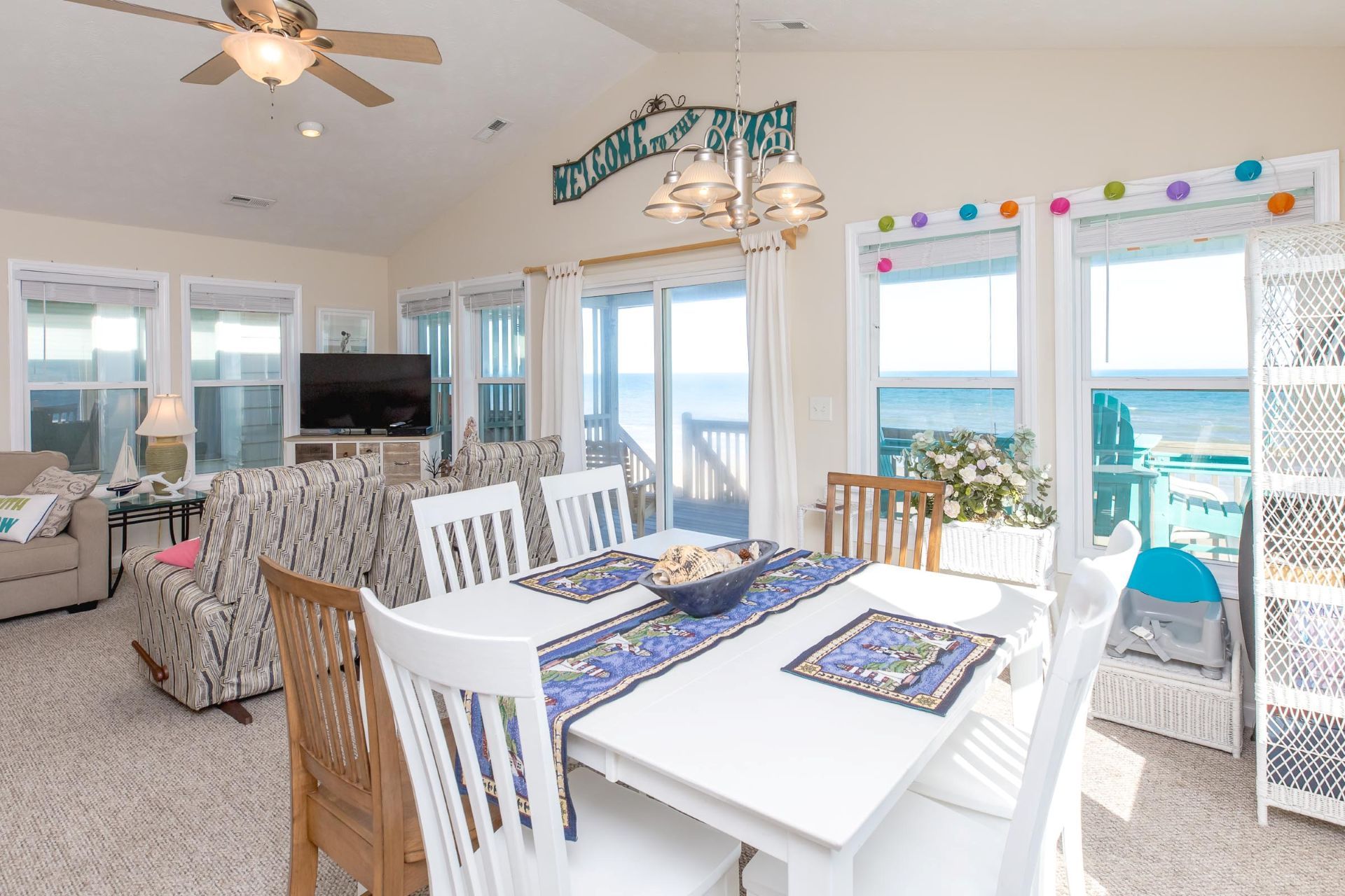 A spacious living area with a television, sofa, and dining table with placemats.