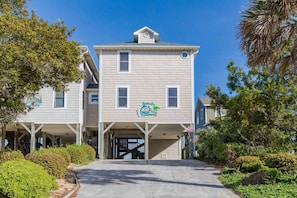 A two-story building with a sign that reads 'Attitude Adjustment' and a covered parking area. - Attitude Adjustment  - 4BR Oceanfront Home; Great Views from the Covered Porches (Surf City)