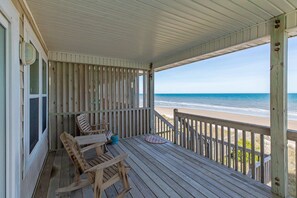 A wooden deck with a view of the beach and ocean.