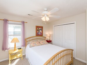 A bedroom with a bed, a ceiling fan, a window with curtains, a bedside table with a lamp, and a door. - Attitude Adjustment  - 4BR Oceanfront Home; Great Views from the Covered Porches (Surf City)
