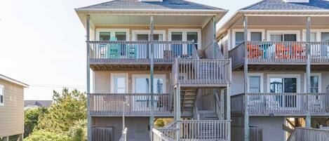 A multi-story building with balconies and a wooden deck leading to the entrance.
