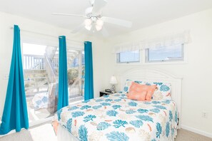 Un dormitorio con cama, ventilador de techo, mesita de noche y ventana con persianas.
