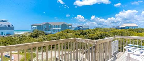 A wooden deck with a view of beachfront houses and ocean.