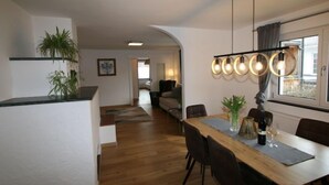 A modern kitchen with a wooden countertop, a dining area with a long table and chairs, and a living room in the background. - Apartment Lisa by Interhome (Achensee)