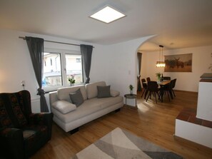 A living room with a sofa, a dining area with chairs and a table, a small side table, and a window with curtains. - Apartment Lisa by Interhome (Achensee)