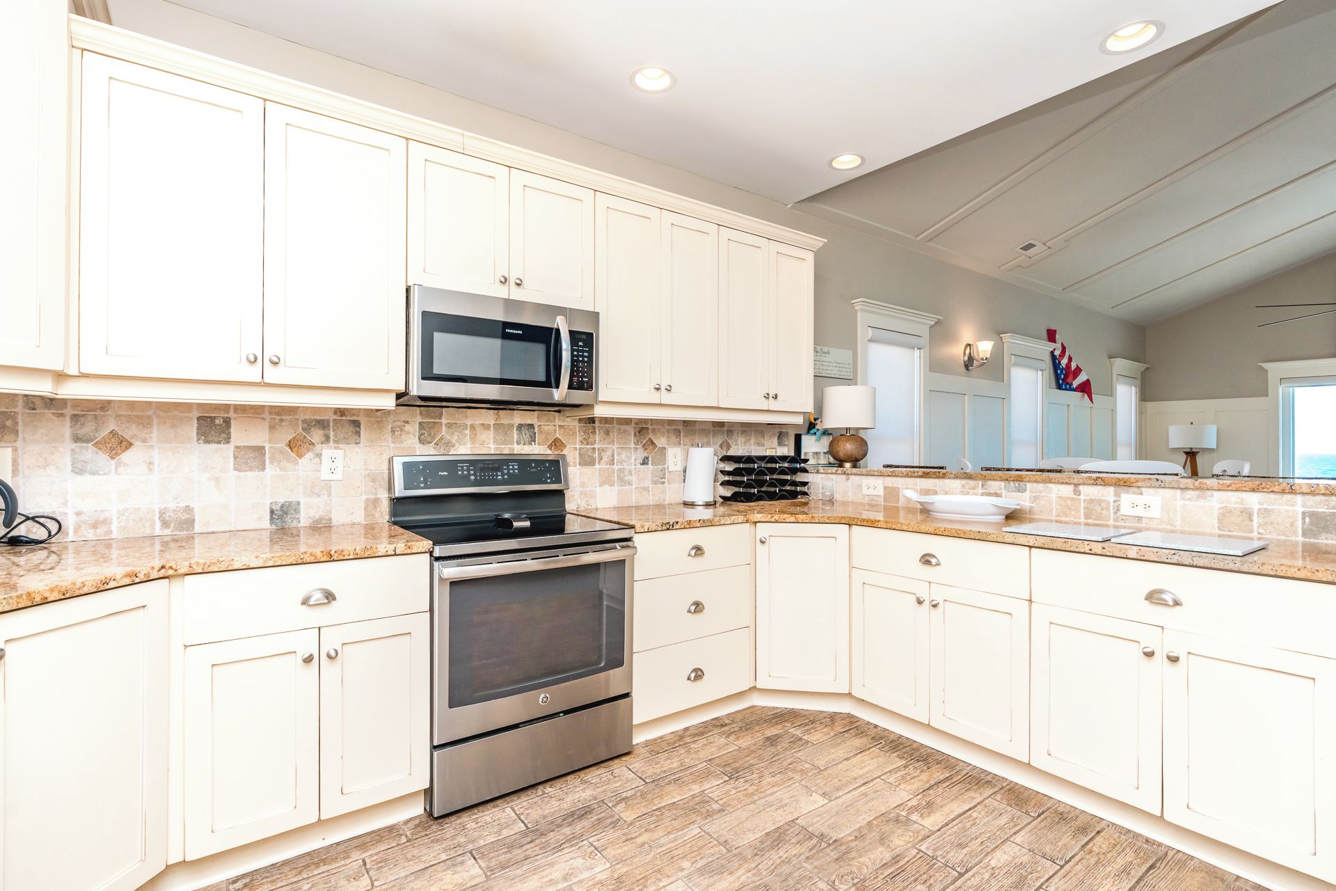 A modern kitchen with white cabinetry, a stainless steel microwave, a built-in oven, and a granite countertop.