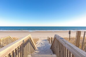 Une promenade en bois qui mène à une plage d’où l’on a une vue dégagée sur l’océan.