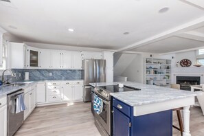 Una cocina moderna con armarios blancos, un refrigerador de acero inoxidable, una isla azul y un horno empotrado.