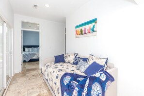 Ein Zimmer mit einem Bett, einem Sofa und einem Gemälde von Strandstühlen.