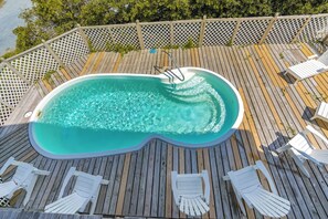 Ein Whirlpool auf einer Holzterrasse, umgeben von weißen Stühlen.