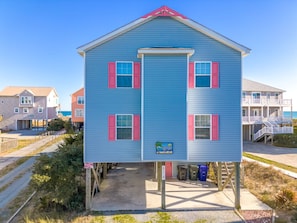 A two-story building with a blue exterior and pink shutters, featuring a small porch area. - Sea-Sun's Greetings! Steps to the beach! Private Pool!  Pet Friendly! (Surf City)