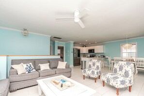 Ein Wohnzimmer mit einem grauen Sofa, einem weißen Couchtisch und gemusterten Sesseln.