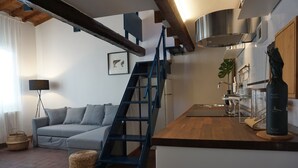 A modern kitchen with a wooden countertop, a blue staircase, and a grey sofa. - Palazzuolo 118 Cozy apartments (Florence)