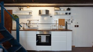 A modern kitchen with white cabinets, a stainless steel range hood, and a built-in oven. - Palazzuolo 118 Cozy apartments (Florence)