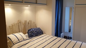 Une chambre à coucher avec un lit, une tête de lit en bois, un miroir et une armoire.