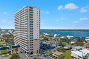 A tall, multi-story hotel with balconies, located near a body of water. - Crystal Tower Beachfront pool/hot tub, indoor heated pool, sauna (Gulf Shores)