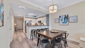 Een moderne keuken met witte kasten, een centraal eiland en barstoelen.