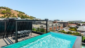 Una piscina infinita en la azotea con vistas a la ciudad y una colina.