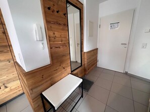 Ein Hotelzimmer mit einer Wandpaneele aus Holz, einer Bank, einem Spiegel und einer Tür mit einem kleinen Schild.
