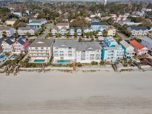 A coastal residential area with a large white building featuring multiple balconies and a swimming pool.
