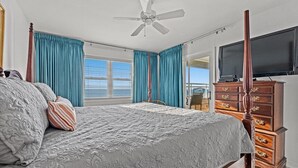 Une chambre à coucher avec un lit à baldaquin, un ventilateur de plafond, une commode en bois et un téléviseur.