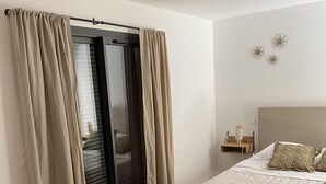 A bedroom with a bed, a woven basket, and a sliding door with curtains.