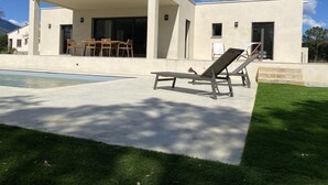 A modern house with a pool, outdoor seating, and a covered patio.