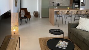 A modern living room with a sofa, a coffee table, and a dining area with chairs.