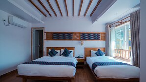 A hotel room with two beds, wooden headboards, a window with curtains, and a view of the outside. - Himalayan Glory Inn (Pokhara)