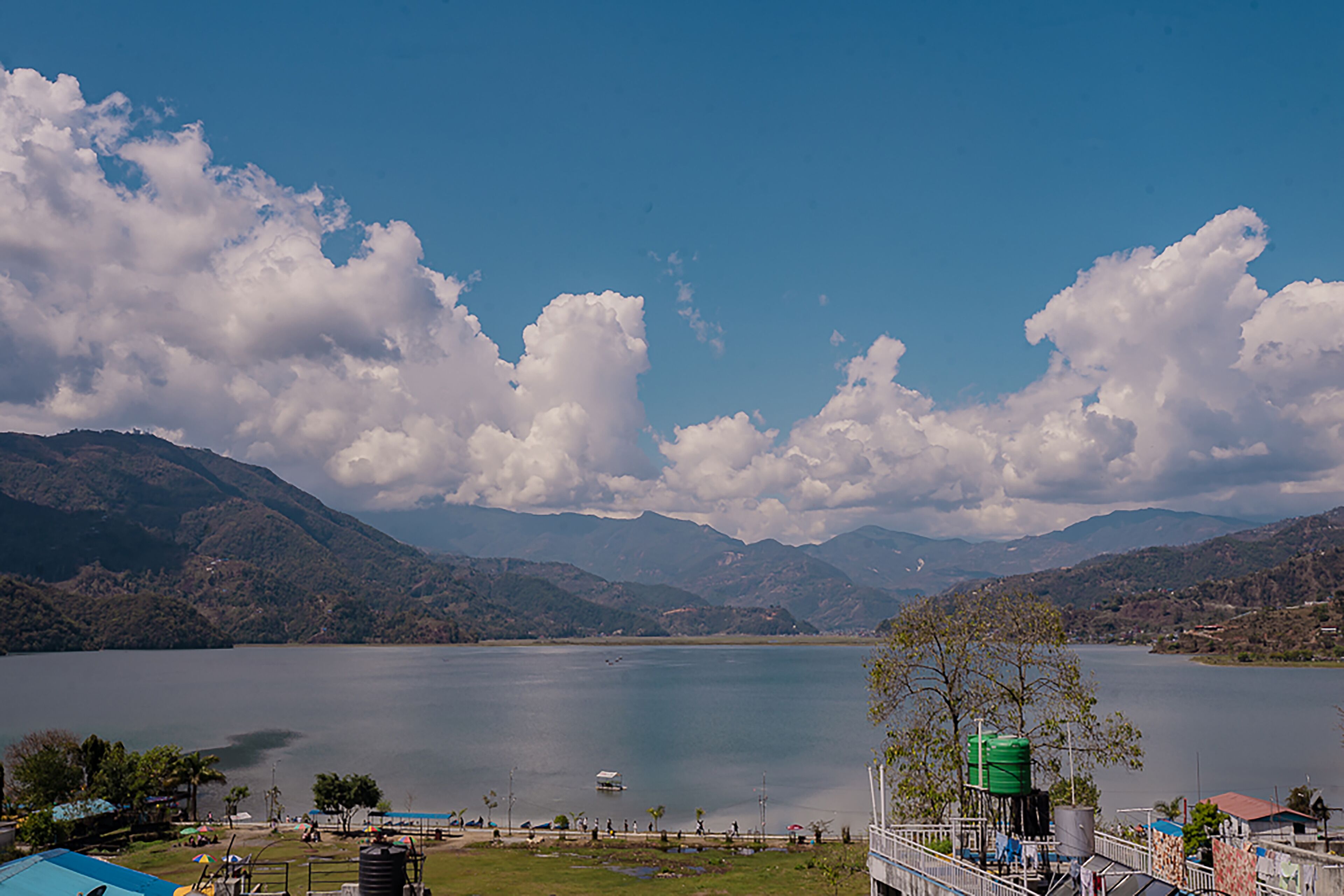 Un llac amb muntanyes al fons, un petit moll i un dipòsit d'aigua verd a la riba.