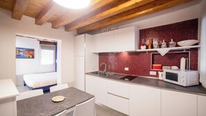A compact kitchen with a sink, microwave, and a red tiled backsplash. - Ca' Gritti (Venice)